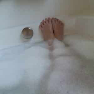 A Girl Socking on the bathing tub with full of water