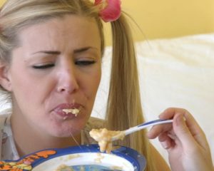 Someone is feeding the girl in the spoon with food.