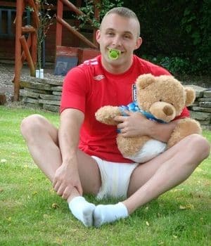 Infant Adult Man with Pacifier in Diaper Holding Teddy Bear