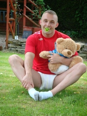 Infant Adult Man with Pacifier in Diaper Holding Teddy Bear