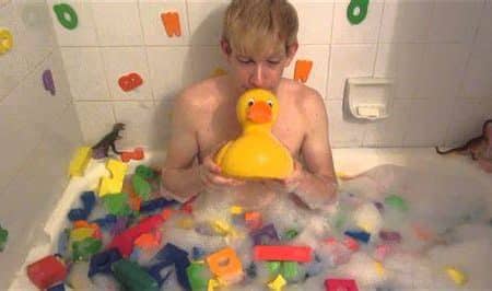 Teen boy play with toys and soap on the belly in the bath water