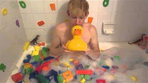Teen boy play with toys and soap on the belly in the bath water