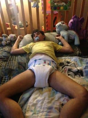 Adult Man Wearing the baby diaper and lying on the bed